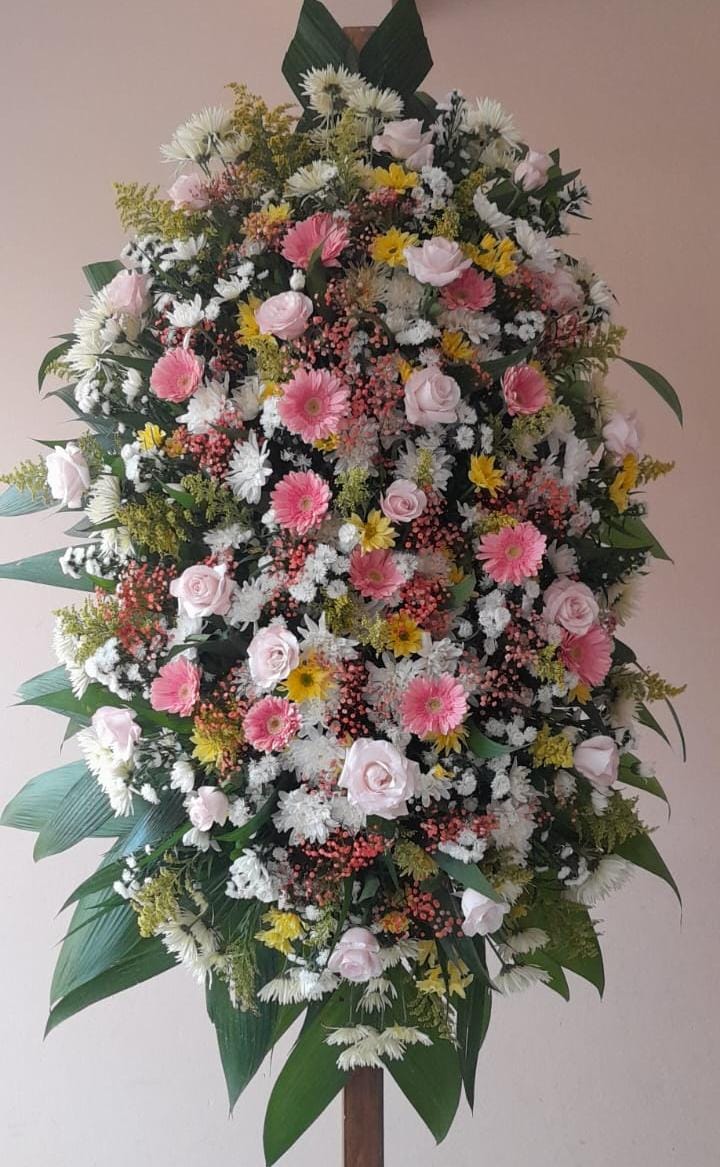 Coroas de flores brancas, amarelas, tons de rosa e folhagens