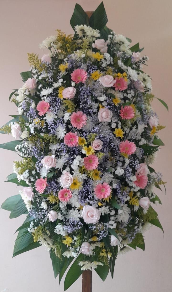 Coroas de flores brancas, amarelas, tons de rosa, lilás e folhagens